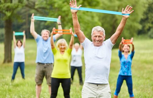 Older adults in park exercising with resistance bands